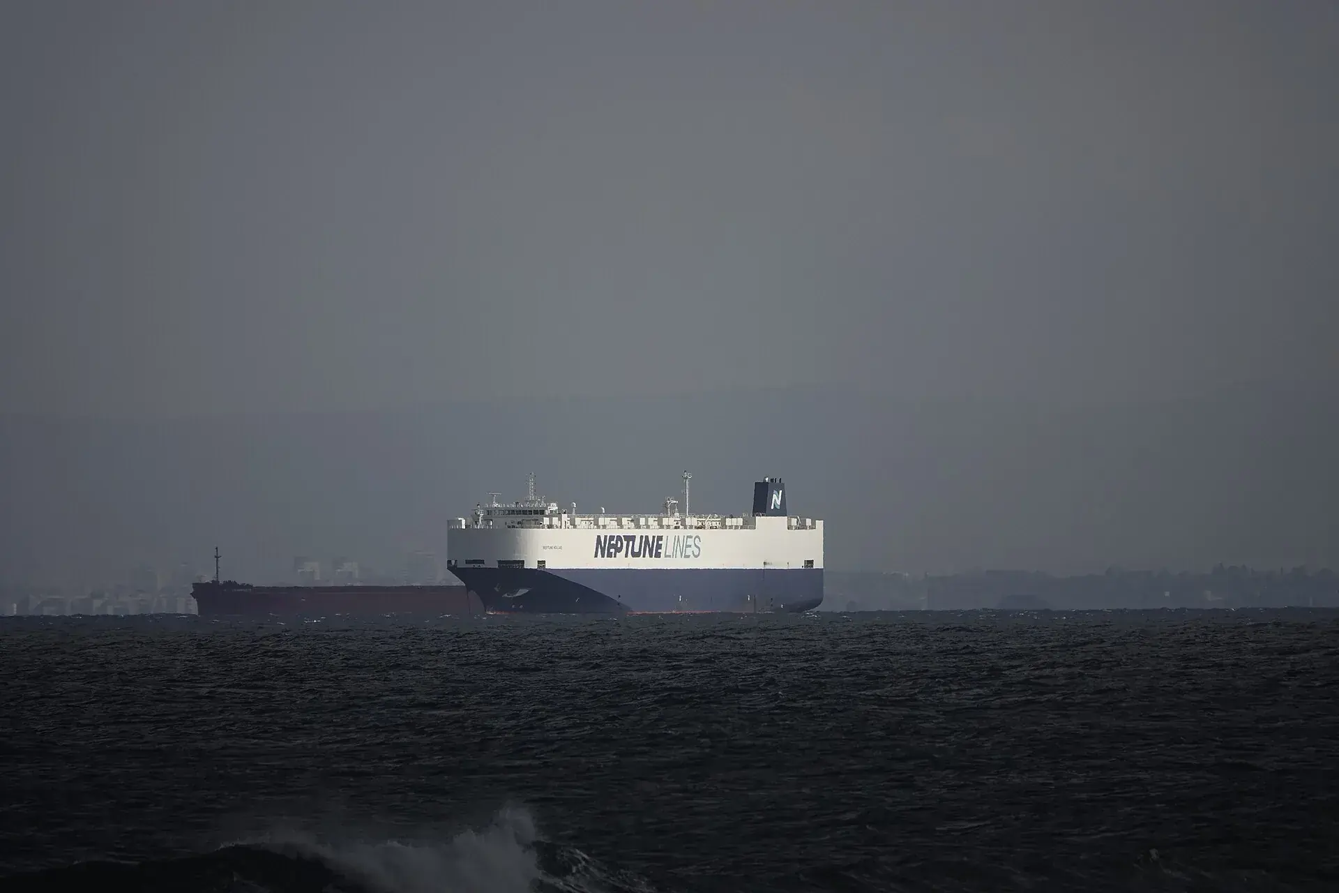 A roll-on/roll-off car carrier ship approaching a commercial port.