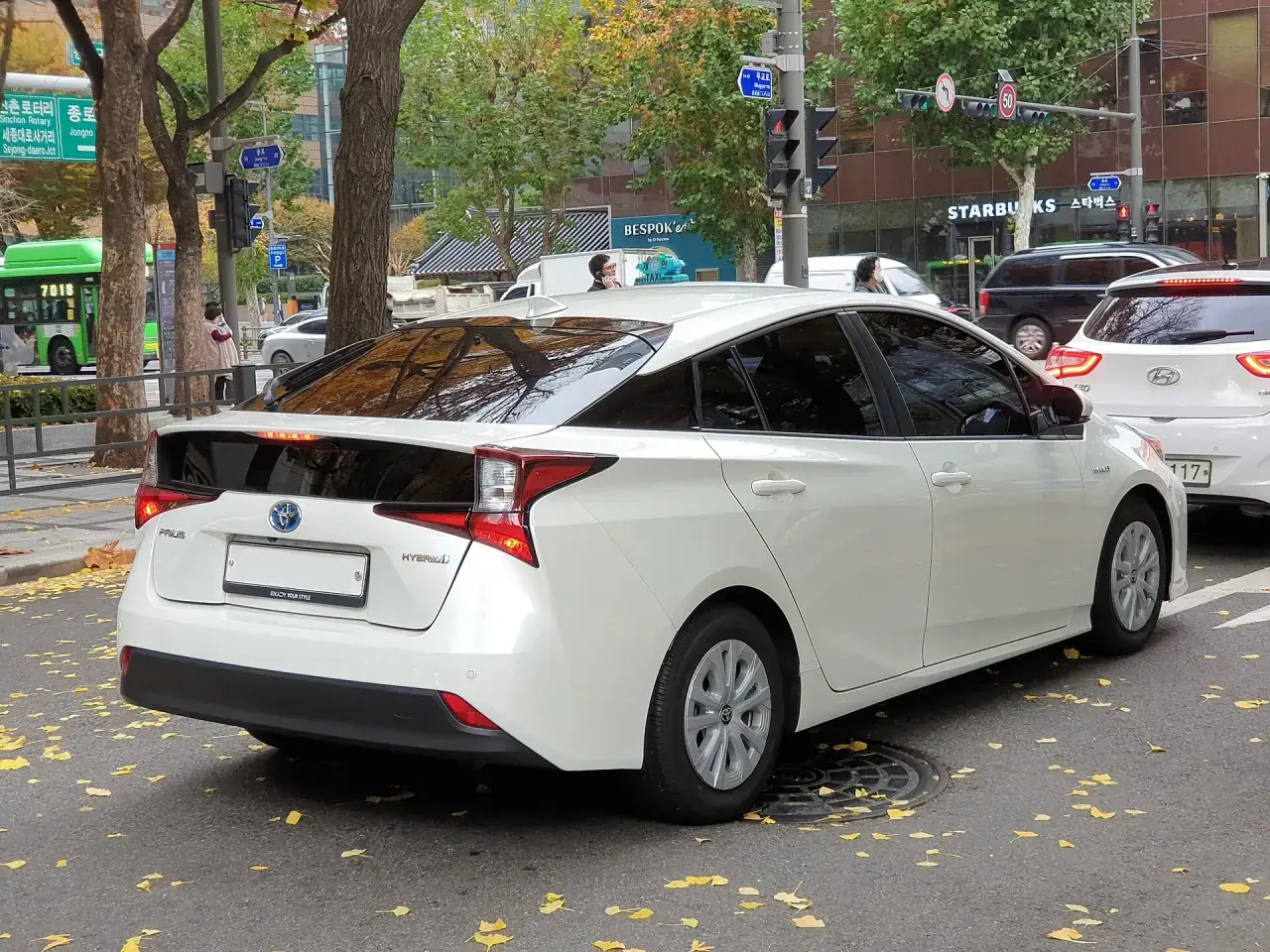 A Japanese hybrid liftback in white pearl, front three-quarter view.