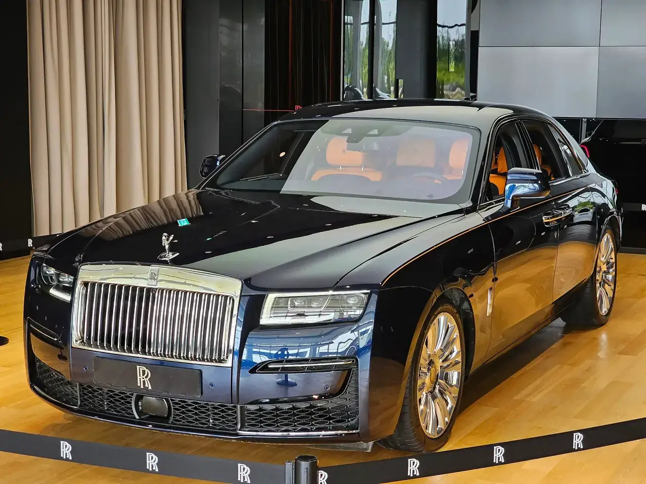 A full-size luxury saloon in deep sapphire blue, front three-quarter view.